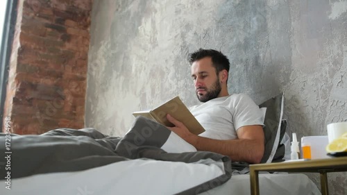 Ill man reading book and feeling sharp twinge of pain