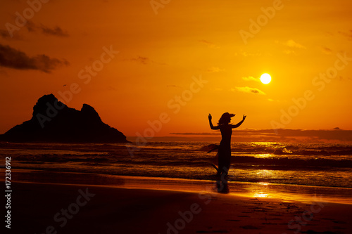 young woman silhouette on the beach in summer sunset light