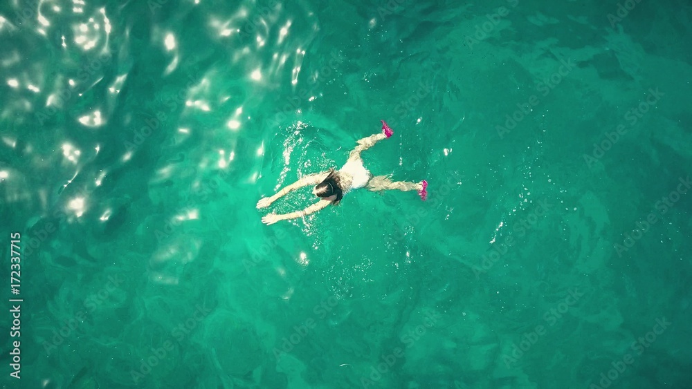 Aerial top down view of a young woman swimming in the sea