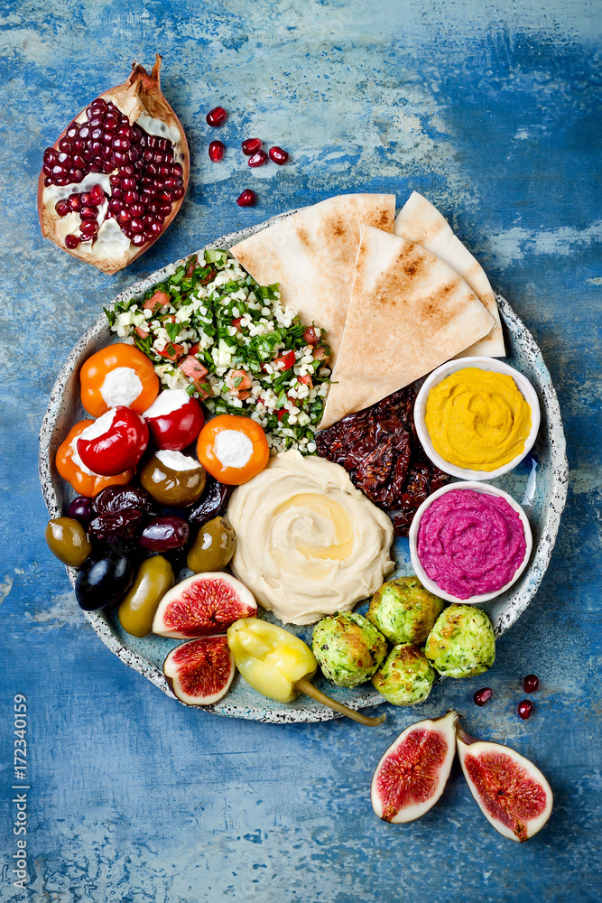 Φωτογραφία Middle Eastern meze platter with green falafel, pita, sun dried tomatoes, pumpkin and beet hummus, olives, stuffed peppers, tabbouleh, figs