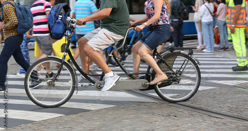 man and woman pedal with tandem in urban road