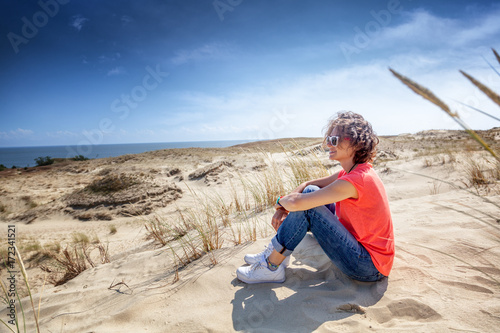 Portrait of a beautiful young woman with short wavy hair, outdoor with sea and white dunes view © olezzo