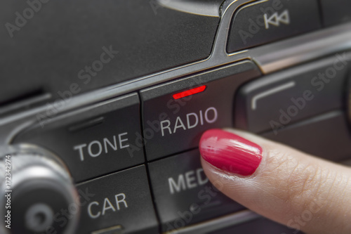 Girl pressing car radio stereo panel and modern dashboard electric equipment close