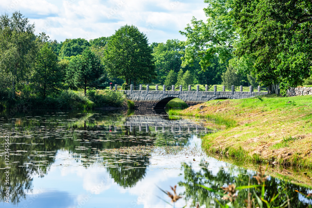 Old stone bridge with arches spanning across narrow river in woodland landscape. Location Vissefjarda in southern Sweden. Old stone bridge with arches spanning across narrow river in woodland landscape. Location Vissefjarda in southern Sweden.