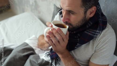 Close up of ill man drinking tea in bed