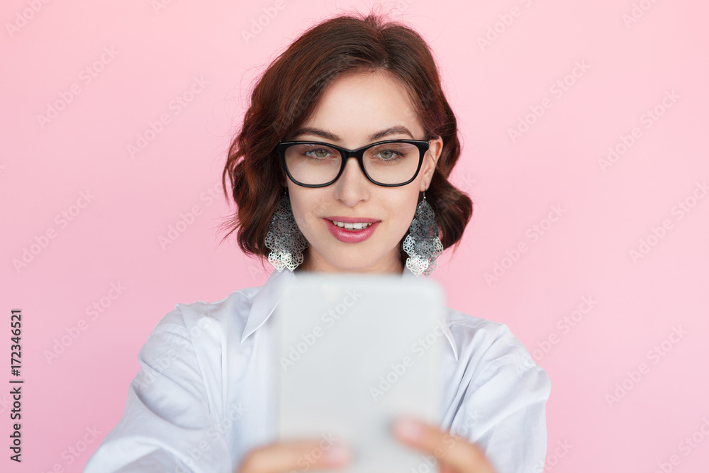 Elegant woman in glasses taking selfie