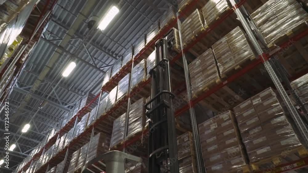 Forklift in the warehouse raises a boxes toward the top shelf. Warehouse materials. Shelves in the warehouse.
Forklift in the warehouse raises a boxes toward the top shelf. Warehouse materials. Shelves in the warehouse.