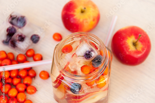 Water with sea buckthorn, forest berries and red apples