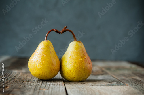 A couple of Fresh ripe organic yellow pears form the shape of the heart on rustic wooden table on the dark gray stone background. Relations, love. care concept. Selective focus. Space for text.