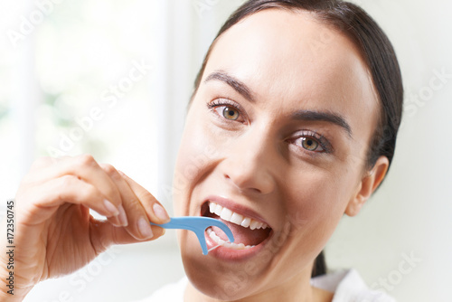 Young Woman Flossing Teeth In Bathroom