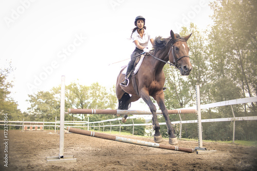 Girl riding a horse and jumping and obstacle © merla