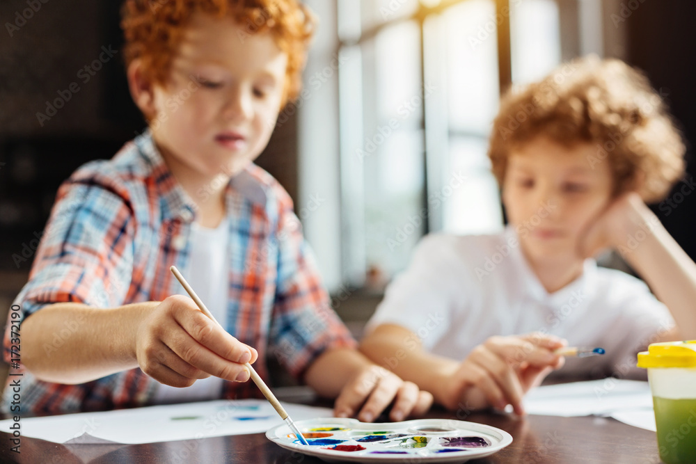 Curly hired children painting at wooden table Curly hired children painting at wooden table