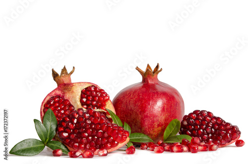 whole Pomegranates and three parts of Pomegranate with leaves and seeds isolated on white