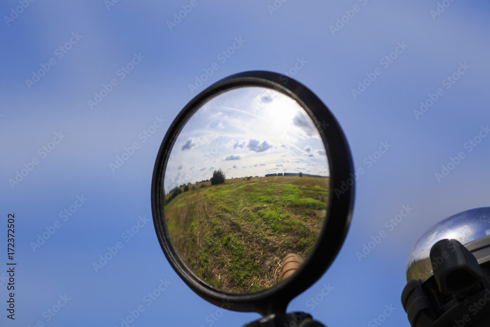 rural landscape with blue sky and field is reflected in the mirror of the bike rural landscape with blue sky and field is reflected in the mirror of the bike