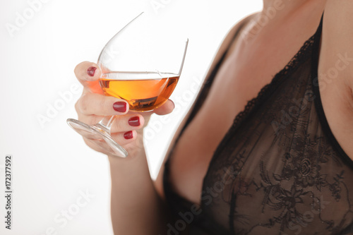 The girl's hand holds a glass of cognac