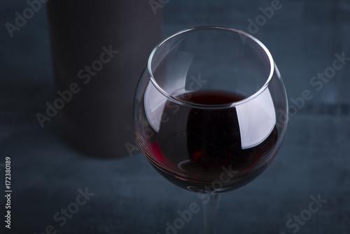 Pouring red wine into the glass against wooden background