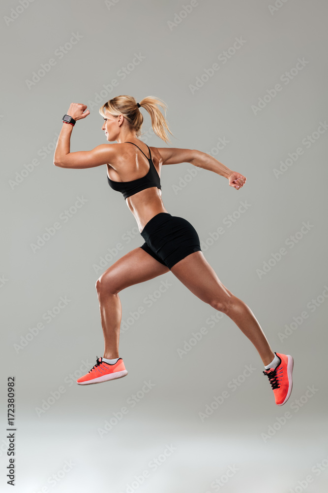 Strong young sports woman running isolated