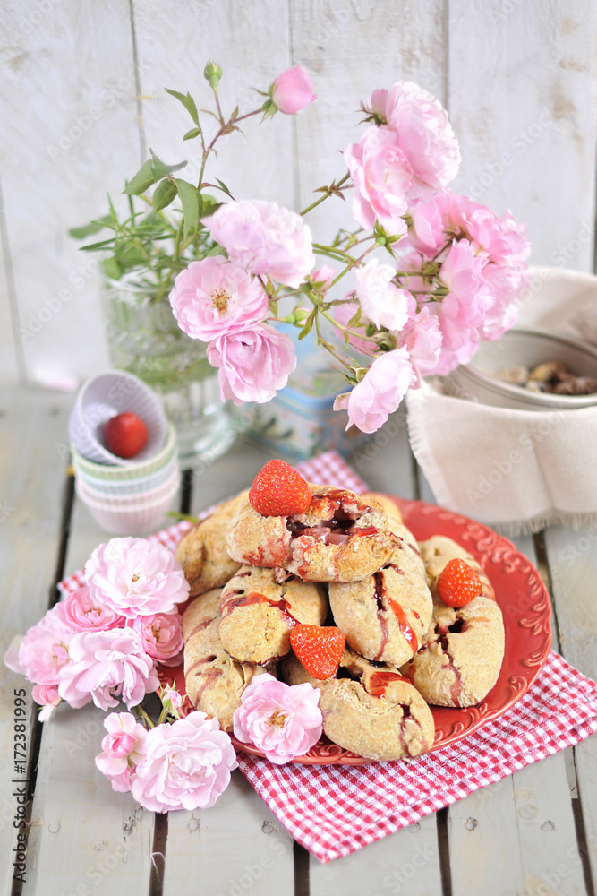 sweet cakes with strawberries. A bouquet of garden roses in a vase. on a light wooden background. Family Breakfast