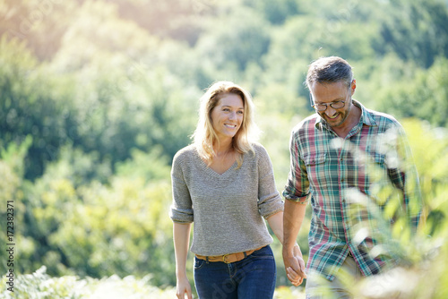Happy mature couple walking in countryside on sunny day photo