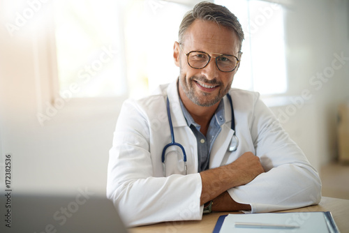 Portrait of mature, doctor sitting in medical office photo