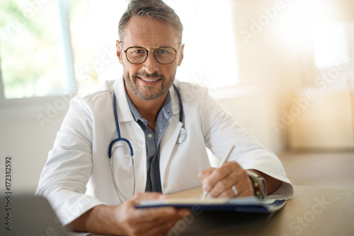 Portrait of mature, doctor sitting in medical office