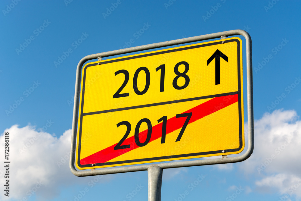 Yellow street sign with the year 2018 ahead leaving 2017 behind Yellow street sign with the year 2018 ahead leaving 2017 behind