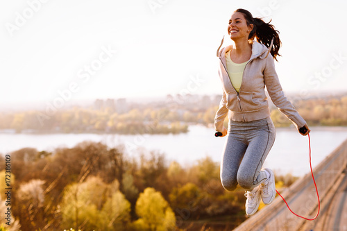 Active woman jumping with skipping rope outdoors photo