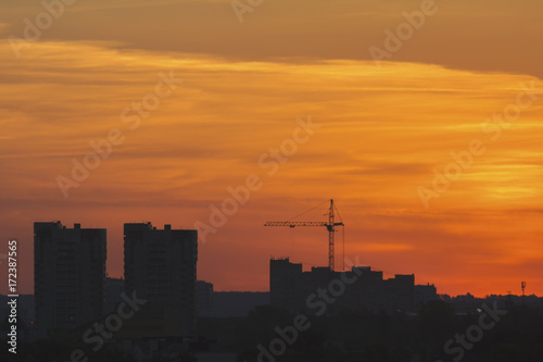 Construction cranes near residential apartments - view on sunrise  horizontal