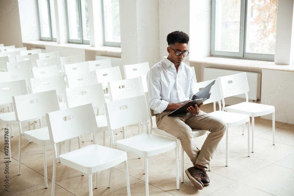 Thinking african man sitting coworking with clipboard Thinking african man sitting coworking with clipboard