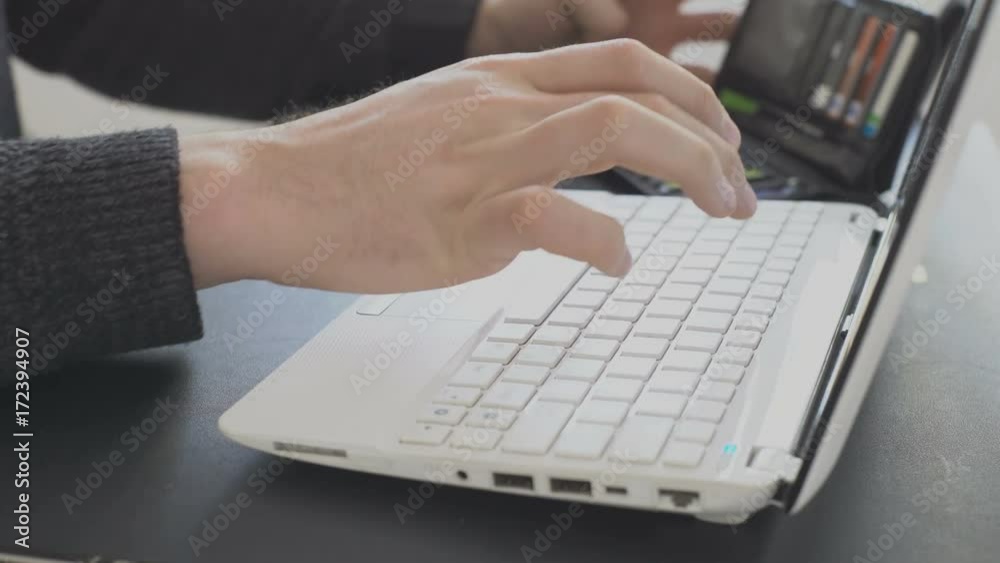 A man (Man's hands), an office worker, sits at home outside his time using a laptop and a bank credit card, pays for online payment in an online store.
