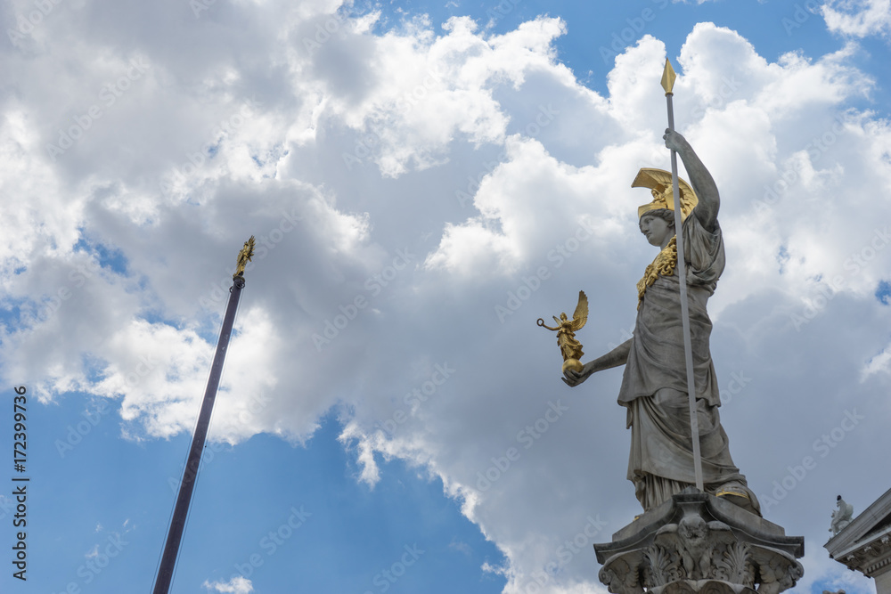 Fototapeta premium Statue and fountain of Pallas Athena Brunnen, greek goddess of wisdom, in golden helmet in front of Parliament building in Vienna, Austria