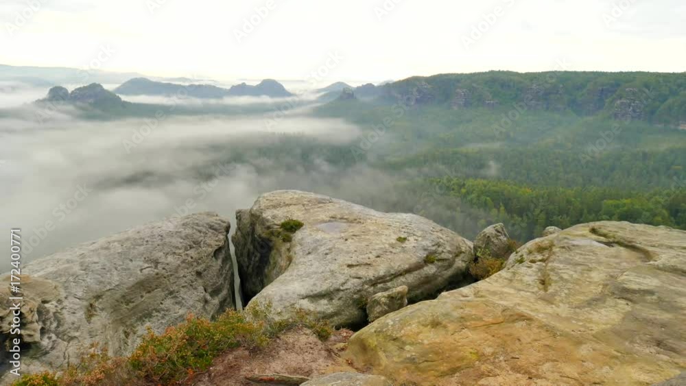 Spring misty morning in forest landscape. View around. Majestic peaks cut lighting mist. Deep valley is full of colorful fog and rocky hills are sticking up to Sun. Spring misty morning in forest landscape. View around. Majestic peaks cut lighting mist. Deep valley is full of colorful fog and rocky hills are sticking up to Sun.