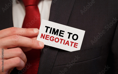 Businessman putting a card with text Time to negotiate in the pocket