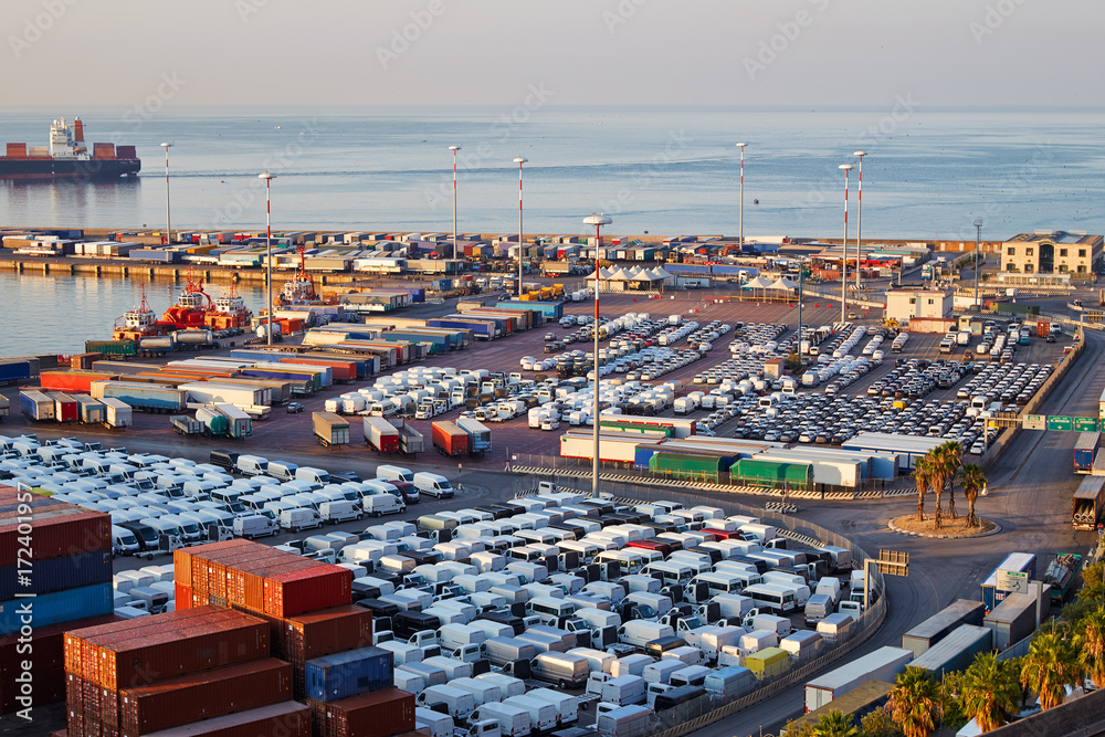 Obraz premium Port terminal with containers, new cars and wagons in the early morning