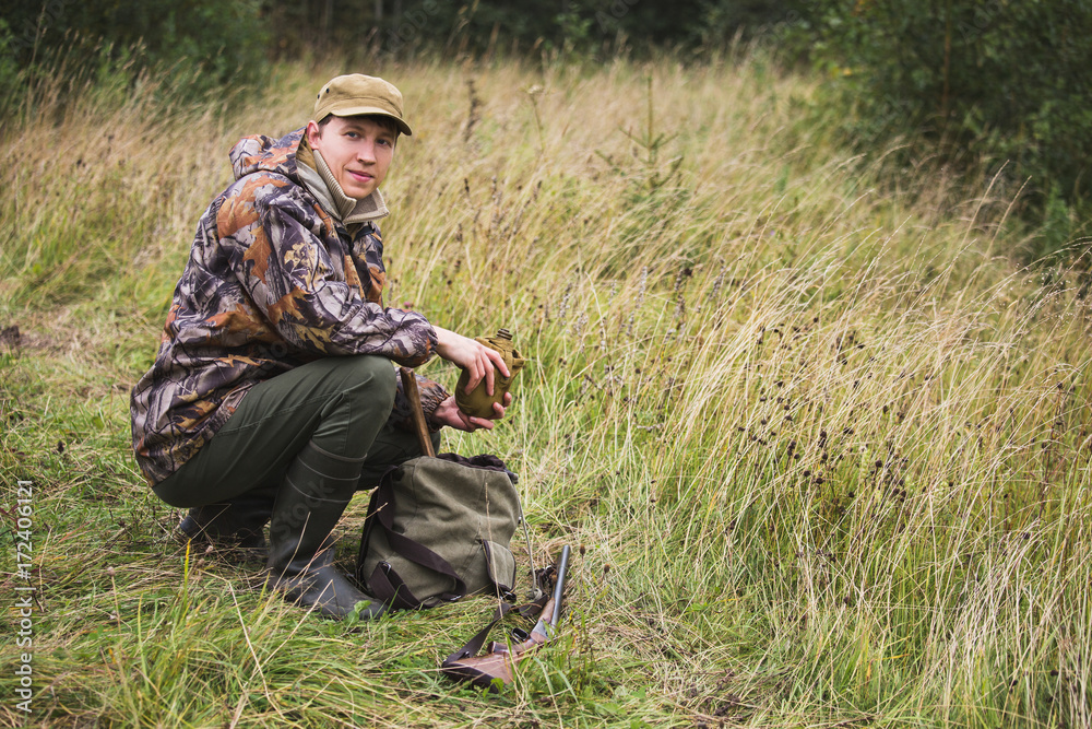 Hunter with a backpack and a hunting gun in the autumn forest. The man is on the hunt.