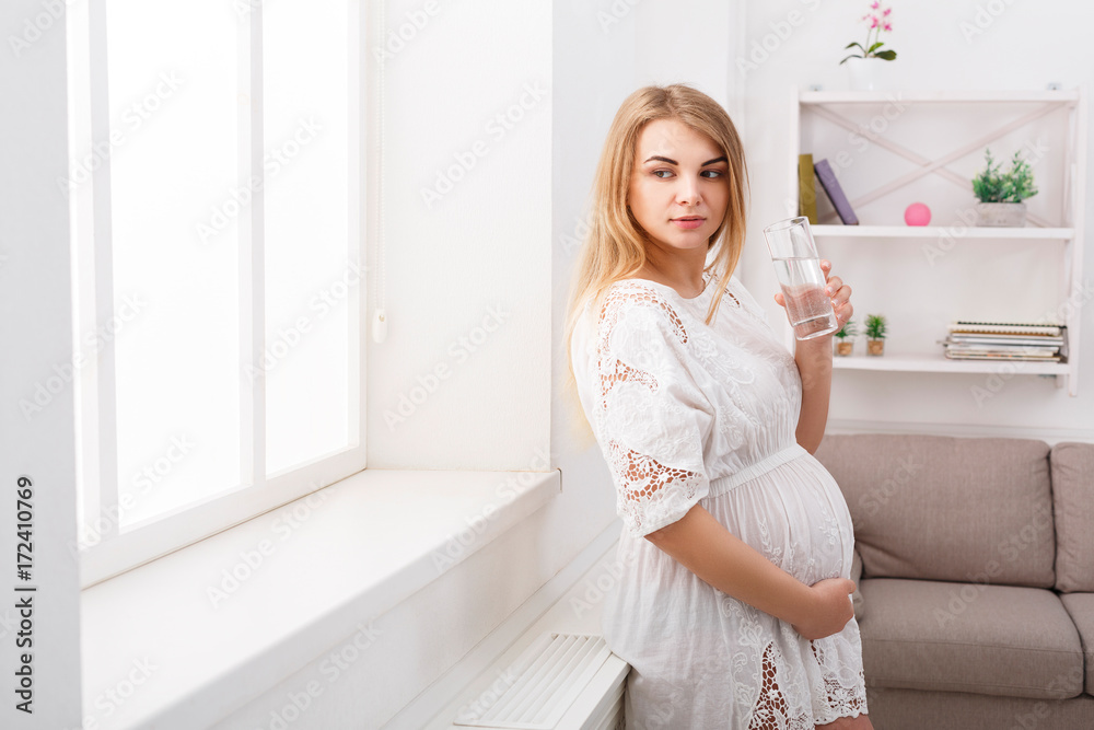 Pregnant woman with glass of water, copy space