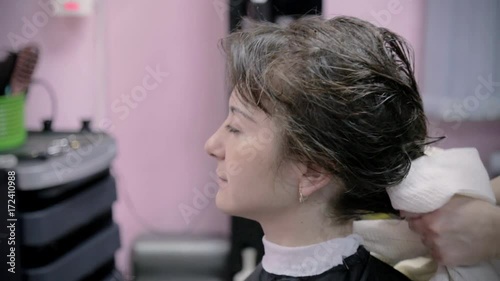 Hairdresser makes hairstyle for young girl. Hairdresser uses the towel