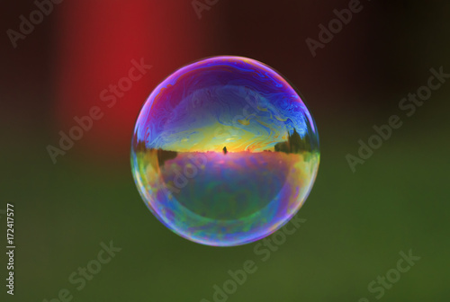 round iridescent soap bubble flying over the Sunny meadow