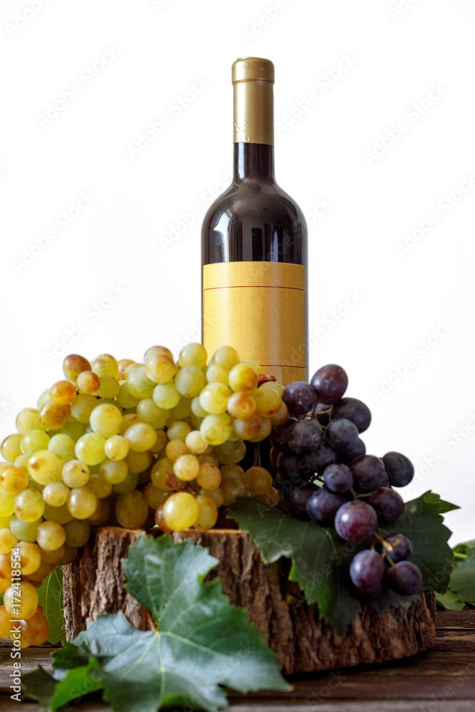 Bottle wine of bunch white and red grape on wooden background.