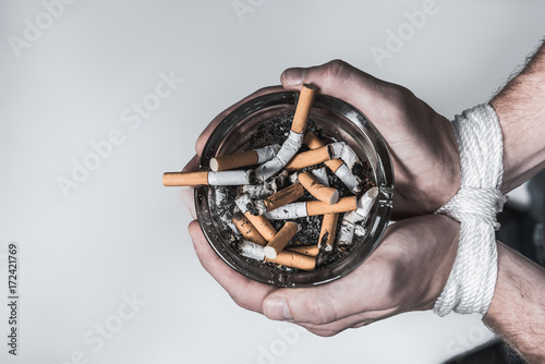 Φωτογραφία Heavy smoker holding ash-pot with tied arms