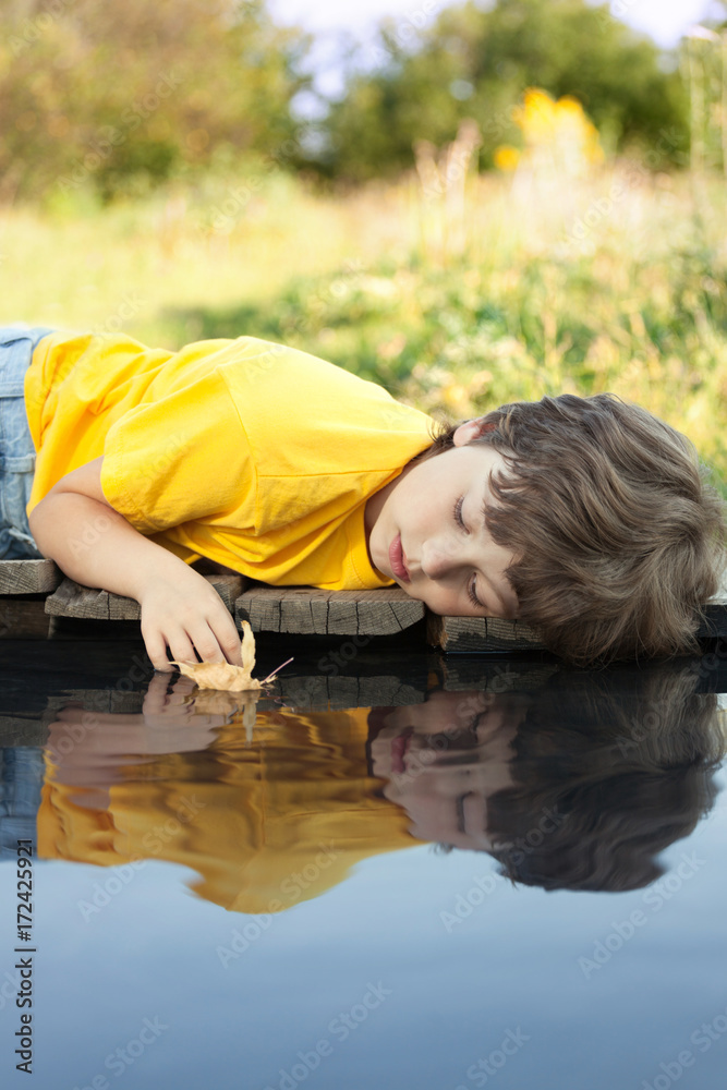 boy play with autumn leaf ship in water, chidren in park play with leaf in river boy play with autumn leaf ship in water, chidren in park play with leaf in river