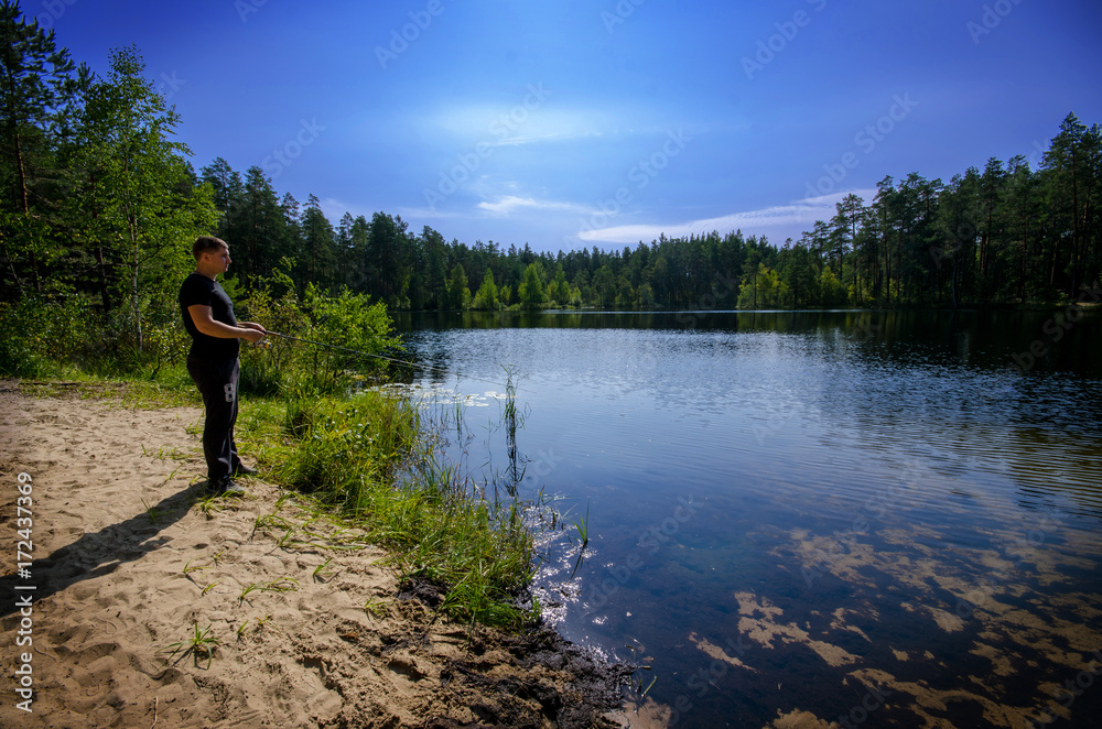 man is fishing on a forest lake