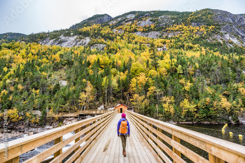 Hike woman with backpack walking in forest nature outdoors bridge. Canada travel hiking tourism at Hautes-Gorges-de-la-Riviere-Malbaie National Park. Active tourist lifestyle.