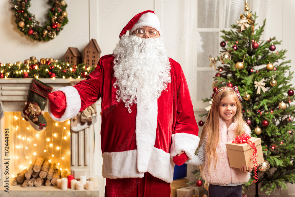 Cheerful kid celebrating winter holiday with Santa Claus