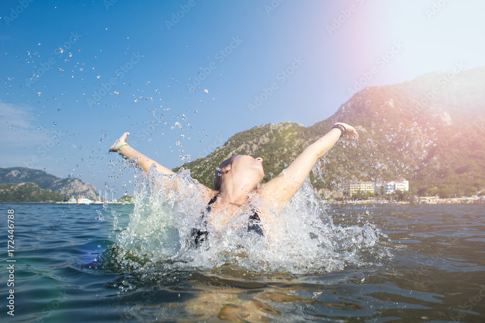 Woman happy jump sea waves splash in tropics on vacation.