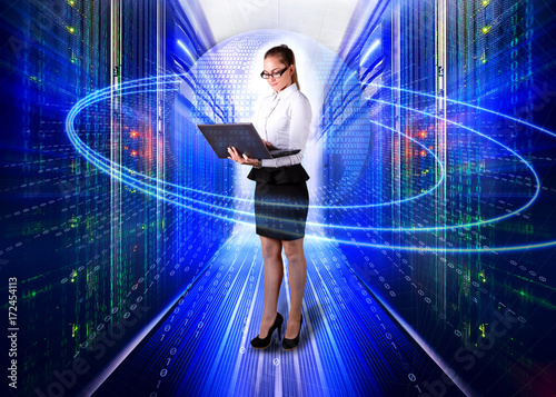 young lady engineer in office clothes standing with laptop in hands on background the server room of data center and futuristic design of concept big data