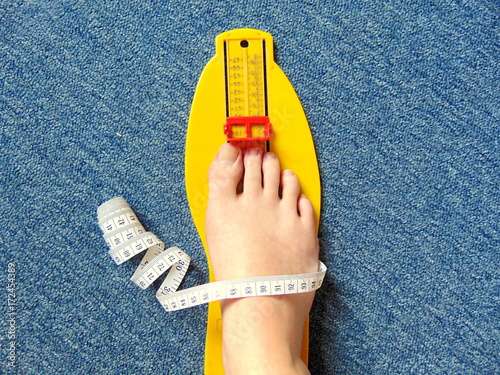 yellow foot measurement device with naked foot upon with measuring tape