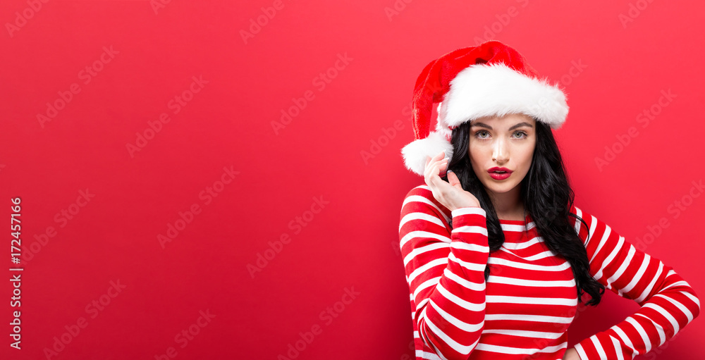 Happy young woman with Santa hat on a solid background
