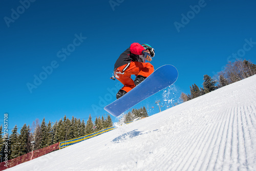 Low angle shot of man snowboarder jumping in the air while snowboarding on the slope at ski resort in the mountains active ski-lift lifestyle winter sports concept Bukovel