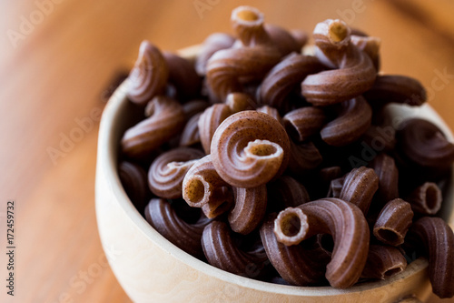 Raw Brown Pasta with Grape seeds in wooden ladle. 